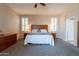 Serene bedroom with plush carpeting, a ceiling fan, a stylish wood bedframe, and bright shuttered windows at 18226 W Stinson Dr, Surprise, AZ 85374