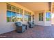 Well-lit covered patio has brick flooring, lounge chairs, and views of the backyard landscaping at 18226 W Stinson Dr, Surprise, AZ 85374