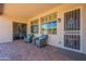 Covered patio with brick flooring features outdoor seating, windows with shutters, and a security door at 18226 W Stinson Dr, Surprise, AZ 85374