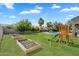 Expansive backyard featuring lush lawn, garden beds, playset, and pool with mature palm trees at 21266 S 213Th Pl, Queen Creek, AZ 85142