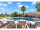 Backyard with pool, surrounded by mature landscaping, lounge chairs, and shaded seating areas at 21266 S 213Th Pl, Queen Creek, AZ 85142