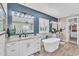 Beautiful bathroom featuring double vanity, soaking tub, blue accent wall, and white cabinets at 21266 S 213Th Pl, Queen Creek, AZ 85142