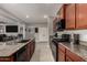 Open concept kitchen featuring granite countertops, wood cabinets, stainless steel appliances, and views to the living room at 23503 S 228Th Pl, Queen Creek, AZ 85142
