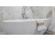 Close-up of a soaking tub with fixtures and marble-look tile in bathroom at 26 W Morten Ave, Phoenix, AZ 85021