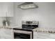 Close-up of kitchen features stainless steel stove and hood, granite counters, subway tile backsplash, and white cabinets at 26 W Morten Ave, Phoenix, AZ 85021