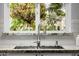 Close-up of kitchen sink showcases granite counters, white cabinets, and a view to a lush, green exterior at 26 W Morten Ave, Phoenix, AZ 85021