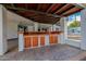Outdoor kitchen with wood cabinetry and a stone floor adjacent to pool at 26 W Morten Ave, Phoenix, AZ 85021