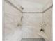 Bright and modern bathroom shower with stone tile, rainfall shower head, seat, and flower decor at 2627 E Gary Way, Phoenix, AZ 85042