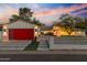 Charming home exterior with a bright red garage door, manicured lawn and vibrant landscaping at 3429 E Coolidge St, Phoenix, AZ 85018