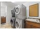 A convenient laundry area boasts stacked washer and dryer units with a sink and cabinet for storage at 3429 E Coolidge St, Phoenix, AZ 85018