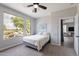 Bright bedroom featuring a ceiling fan, neutral walls, large windows with neighborhood views, and a doorway to a bathroom at 36047 N Copper Hollow Way, Queen Creek, AZ 85140