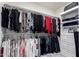 Walk-in closet with rods and shelving with an arrangement of clothing and handbags at 41825 W Mesquite Rd, Maricopa, AZ 85138