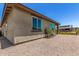 View of a tan house exterior with rock landscaping, windows, and partial view of covered patio at 41825 W Mesquite Rd, Maricopa, AZ 85138