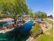 Beautiful pond with mature trees, lush landscaping, and a tranquil waterfall feature at 41825 W Mesquite Rd, Maricopa, AZ 85138