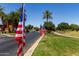 Festive street adorned with American flags, palm trees and lush green grass at 41825 W Mesquite Rd, Maricopa, AZ 85138