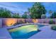 Beautifully lit backyard pool with a waterfall feature and privacy landscaping, perfect for evening relaxation at 490 W Encinas St, Gilbert, AZ 85233