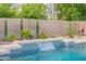 Close up of a private pool featuring a modern waterfall feature, tiled accents, and lush landscaping at 490 W Encinas St, Gilbert, AZ 85233