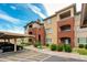 Exterior view of a multi-story apartment complex with carports, parking and well-maintained landscaping at 5401 E Van Buren St # 1004, Phoenix, AZ 85008