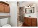 Bathroom featuring a tiled walk-in shower, vanity with wood cabinets, and a decorative mirror at 6837 W Camelback Rd, Phoenix, AZ 85033
