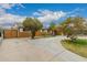 Suburban home with a large concrete driveway, mature trees, and a secure fenced yard at 6837 W Camelback Rd, Phoenix, AZ 85033