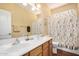 Well-lit bathroom with double sinks, wooden cabinets, and a shower-tub combination at 726 E Heather Dr, San Tan Valley, AZ 85140