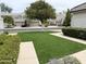 Home featuring a beautifully landscaped front yard with lush green lawn, mature tree, and well-manicured bushes at 7272 E Gainey Ranch Rd # 122, Scottsdale, AZ 85258
