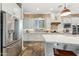 Gourmet kitchen with stainless steel fridge, brick accent, white cabinetry and center island with seating at 7503 S Roanoke St, Gilbert, AZ 85298