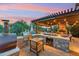 Outdoor kitchen area with built-in grill, pizza oven, and bar seating, ideal for backyard entertaining at 7503 S Roanoke St, Gilbert, AZ 85298