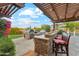 Outdoor kitchen with stainless steel grill, pizza oven, bar seating, and pergola, creating an ideal space for entertaining at 7503 S Roanoke St, Gilbert, AZ 85298