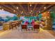 Outdoor covered patio with string lights, stone fireplace, grill, bar seating, and relaxing views of the pool at 7503 S Roanoke St, Gilbert, AZ 85298