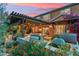 Beautiful outdoor kitchen features a built-in grill, stone accents, pergola, and colorful flowers at 7503 S Roanoke St, Gilbert, AZ 85298