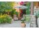 Secluded outdoor seating area featuring comfortable chairs, a side table, lush greenery, and a shaded umbrella at 7503 S Roanoke St, Gilbert, AZ 85298