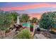 Relaxing backyard pool with fountains, lounge chairs, and lush landscaping against a sunset sky at 7503 S Roanoke St, Gilbert, AZ 85298