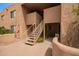Exterior view of a tan building with concrete walkway and staircase leading to upper level condos in a lush landscape at 8155 E Roosevelt St # 205, Scottsdale, AZ 85257