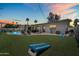 Evening shot of the backyard showcasing a sparkling pool, covered patio, and a vibrant sunset sky at 8315 E Devonshire Ave, Scottsdale, AZ 85251