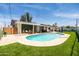 Spacious backyard with a sparkling pool, manicured lawn, outdoor dining area, and a covered patio at 8315 E Devonshire Ave, Scottsdale, AZ 85251