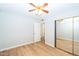 A simple bedroom featuring wood-look flooring, neutral walls, and a mirrored closet at 909 W San Mateo Ct, Gilbert, AZ 85233
