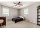 Bright bedroom with two windows, a ceiling fan, and dark wood furniture at 14727 W Pasadena Ave, Litchfield Park, AZ 85340