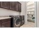 Laundry room with dark cabinets, stainless steel washer and dryer and walk-in shelving at 14727 W Pasadena Ave, Litchfield Park, AZ 85340