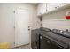 Laundry room featuring overhead cabinets, modern washer and dryer, and a white painted door at 1540 E Glencove St, Mesa, AZ 85203