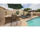 Inviting pool area with an outdoor kitchen, lounge chairs, and lush greenery, ideal for relaxation at 16036 W Desert Bloom St, Goodyear, AZ 85338