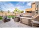 Well-landscaped backyard with outdoor kitchen, fireplace, and cozy seating area at 22259 N 102Nd Ln, Peoria, AZ 85383