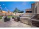 Stylish outdoor area featuring a built-in barbecue and stone fireplace under the ambient glow of string lights at 22259 N 102Nd Ln, Peoria, AZ 85383