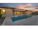 Backyard pool at dusk featuring travertine decking and seamless flow to the house at 24138 S 220Th St, Queen Creek, AZ 85142