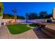 Backyard featuring a fire pit, pool, and deck, enhanced by strategic lighting and lush landscaping under a twilight sky at 3133 E Claire Dr, Phoenix, AZ 85032