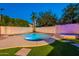 Nighttime view of a backyard featuring a sparkling pool, lush lawn, and ambient lighting, perfect for evening relaxation at 3133 E Claire Dr, Phoenix, AZ 85032
