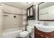 Functional bathroom with a combined tub and shower, tiled walls, storage, and a stylish vanity at 3358 W Sandra Ter, Phoenix, AZ 85053