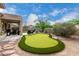 Expansive backyard with a custom putting green, covered patio, and lush desert landscaping at 3460 N Stone Gully St, Mesa, AZ 85207