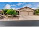 Tan home featuring a three car garage, desert landscaping, and a beautiful blue sky above at 3460 N Stone Gully St, Mesa, AZ 85207