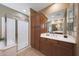 A luxurious bathroom featuring wood cabinets, double sinks, a walk-in shower and a large mirror at 3521 N Hooper St, Buckeye, AZ 85396